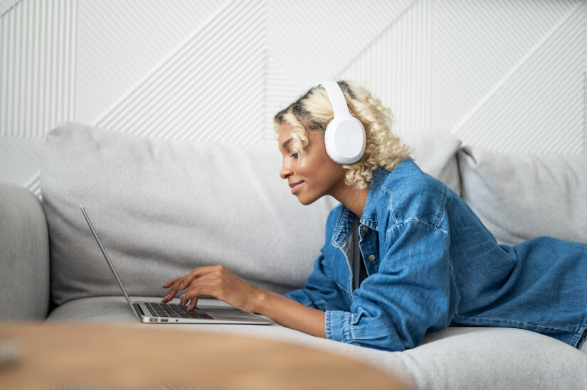 Developer listening to music, working on sofa with laptop