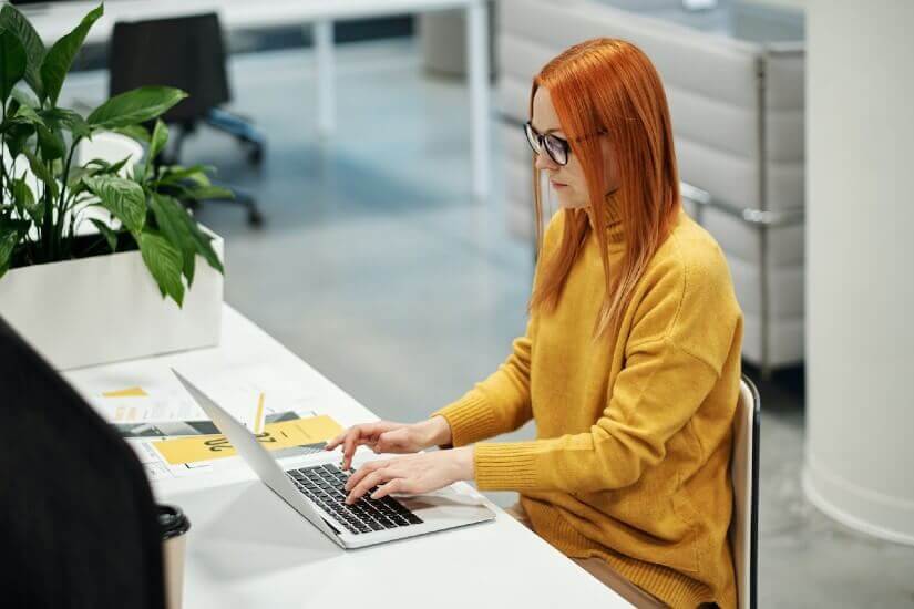 A woman in yellow typing on a computer
