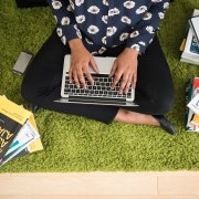 Woman sitting on the floor with a laptop on her lap.