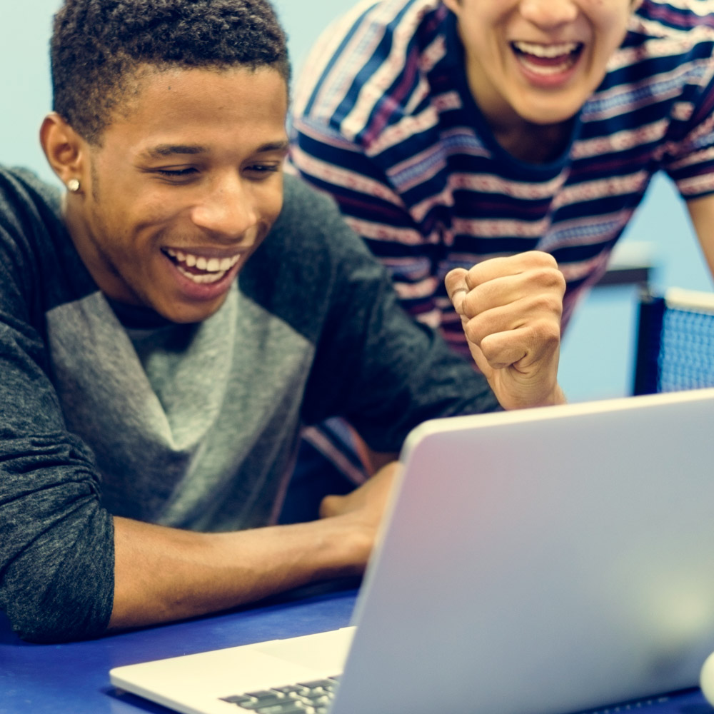 Two men celebrating as they look at a laptop&#39;s screen.