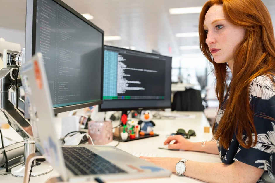 Woman coding on three computer screens