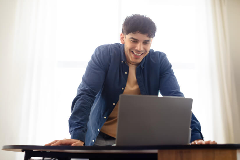 Smiling programmer standing after laptop
