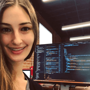 Tassia Profile pic with computer monitor that has code on it in background Women In Tech